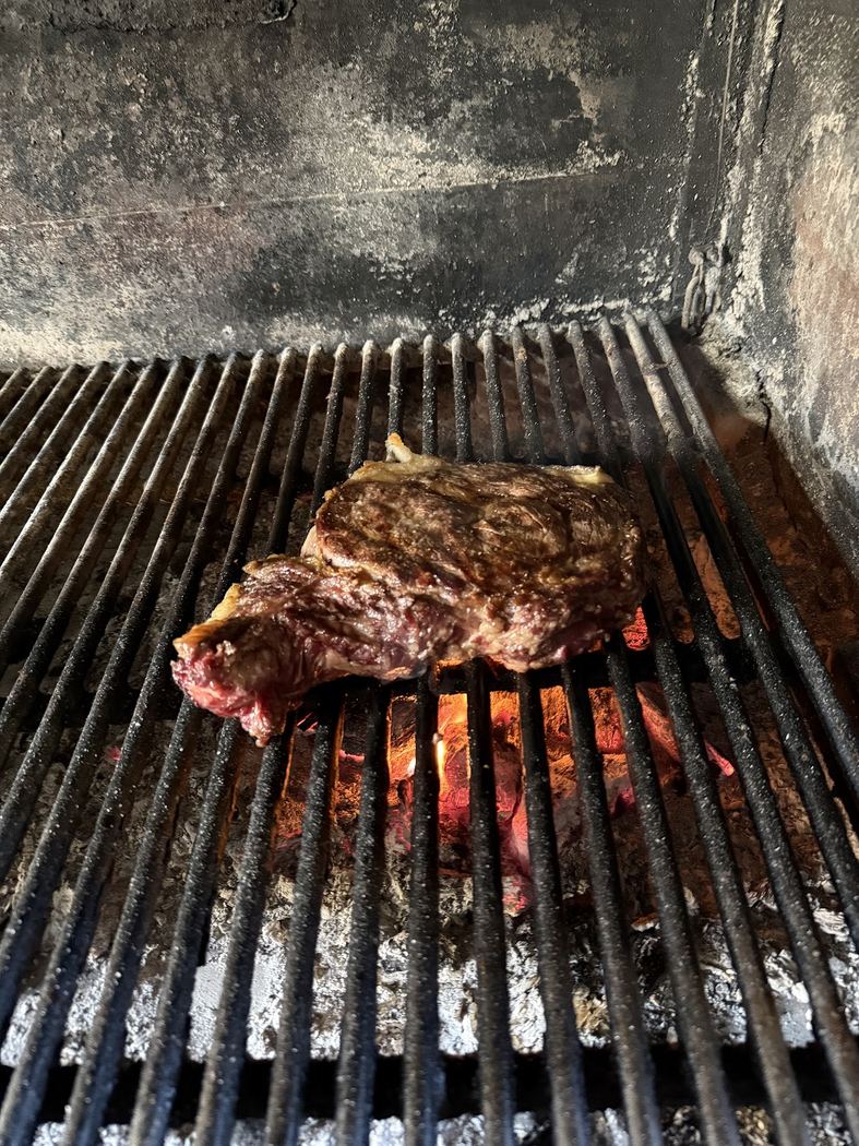 Chuletón a la parrilla, carne jugosa cocinada lentamente sobre brasas.